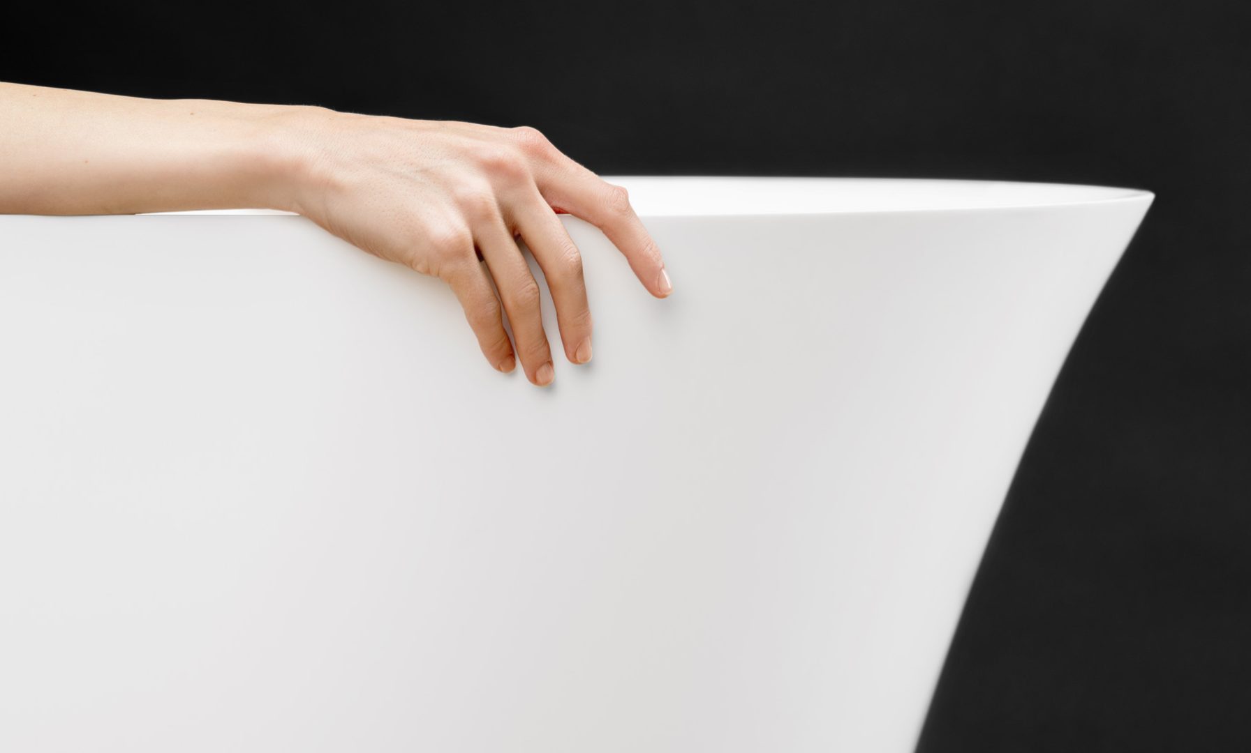 Fiore bathtub with a woman’s hand on the edge in a wellness and spa setting