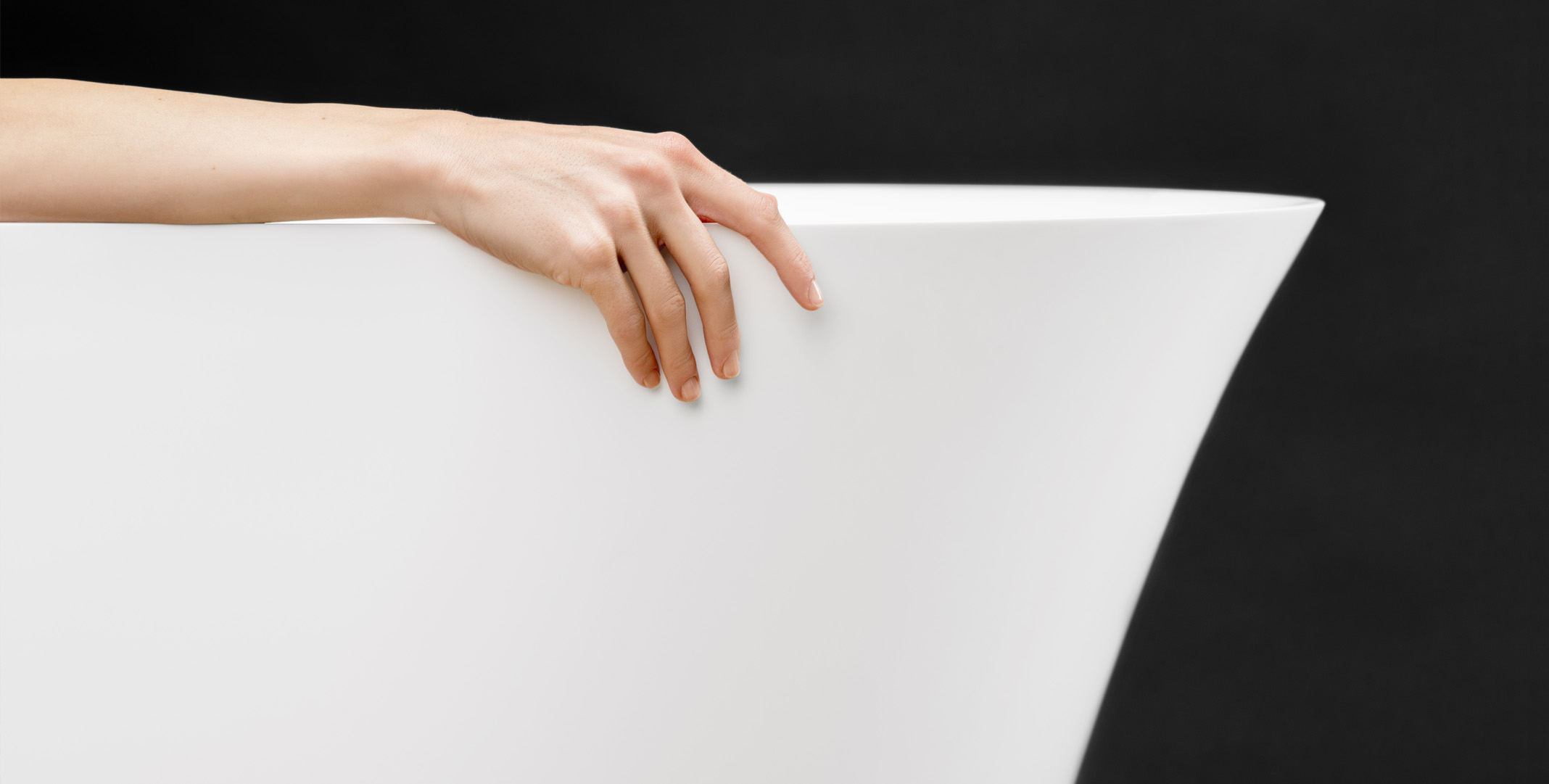 Fiore bathtub with a woman’s hand on the edge in a wellness and spa setting